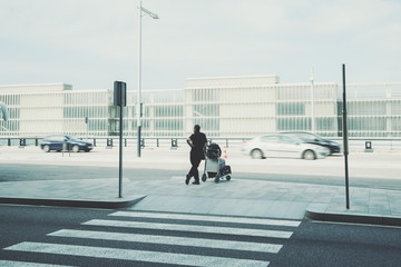 Rear view of man with luggage standing in front of air traffic control tower near airport parking, experienced male employer with suitcase waiting for taxi outdoors near airport terminal in Barcelona