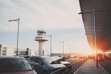 Fotobehang Luchthaven Parkeerplaats, weg en taxistandplaats in de buurt van moderne hedendaagse luchthaventerminal voor luchtverkeersleidingstoren, met veel passagiers en personeel die op afstand passeren, Barcelona, Spanje
