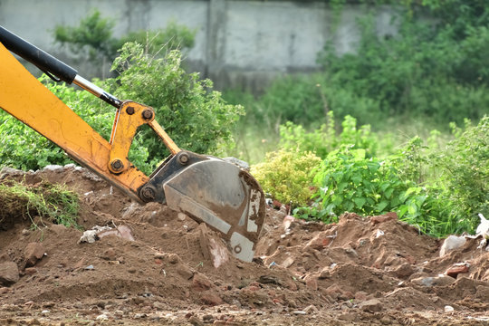 Excavator is working with dusty red soil.