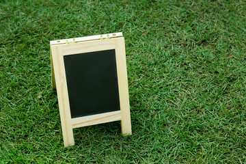 Black board with easel on green grass background