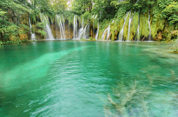 Multiple stunning waterfalls cascade into a vibrant turquoise lake at one of the oldest   and most visited national parks in Europe, Plitvice Lakes National Park.