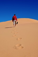 Man walking on sand dunes to the sky. Coral Pink Sand Dunes State Park. Cedar City. Kanab. Utah. United States.