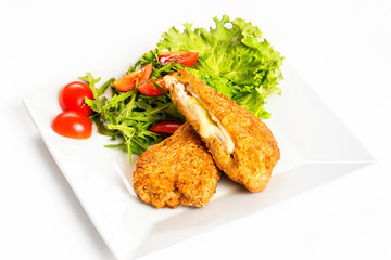 Fried golden chicken with cheese and vegetables on plate isolated at white background.