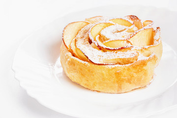 Sweet rose style twisted cake of pastry puff on plate isolated at white background.