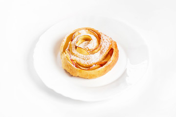 Obraz na płótnie Canvas Sweet rose style twisted cake of pastry puff on plate isolated at white background.