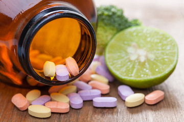Vitamin C pills, broccoli and lemon on a wooden table, supplemental diet, healthcare and wellness concept