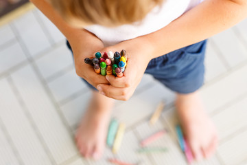 child's hands with lots of colorful wax crayons 