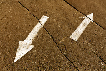 Naklejka premium Two arrows on orange cracked asphalt surface.