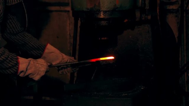 Large mechanical hammer hits hot metal/ Man working at the forge. Worker heavy metallurgy