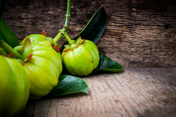 Close up of garcinia cambogia fresh fruit on wood background. - obrazy, fototapety, plakaty