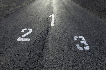 Sunny straight race asphalt road with painted first, second and third place numbers on the floor.