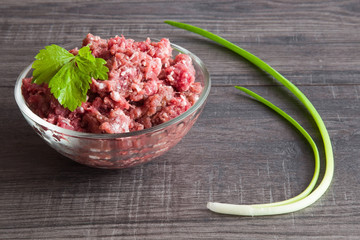 Minced meat in the bowl on the wooden table in the kitchen. Healthy eating and lifestyle.