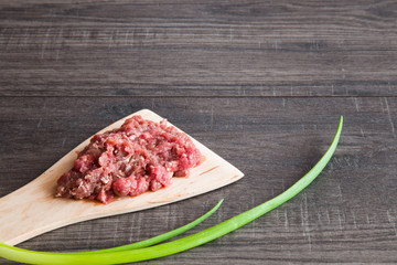 Minced meat on the wooden spoon in the kitchen. Healthy eating and lifestyle.