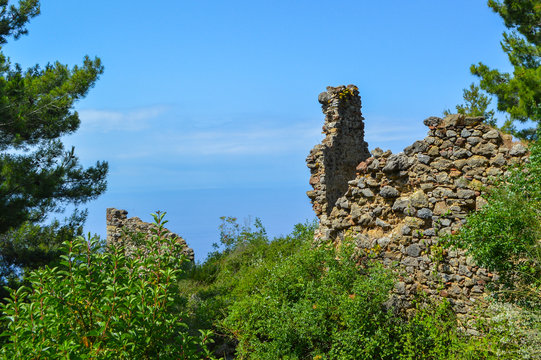 Ancient stone ruins overlooking the sea under a clear blue sky. Mediterranean coastal landscape, history, archaeology, travel and nature background