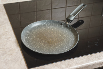 Blank thin frying pan pancakes on the induction hob prepared in the kitchen.