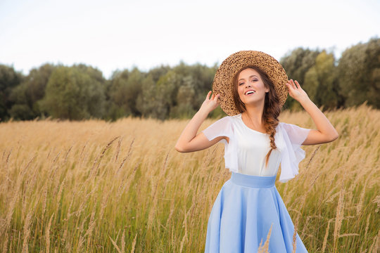 Girl with circlet of flowers walking in golden dried grass field