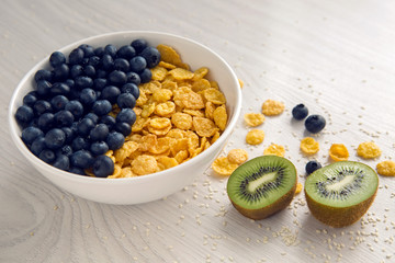 granola with blueberries in white bowl on wooden white background