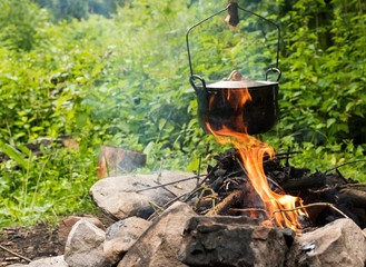 Cooking in caldron. Preparing food on campfire in wild camping. Cooking in a pot on the campfire....