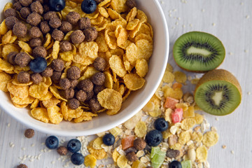 granola with blueberries in white bowl on wooden white background