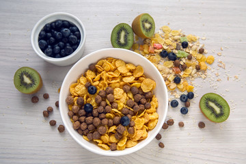 granola with blueberries in white bowl on wooden white background