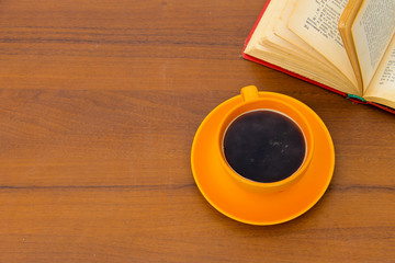 Cup of coffee and old book on wooden desk