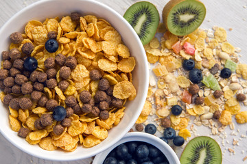 granola with blueberries in white bowl on wooden white background