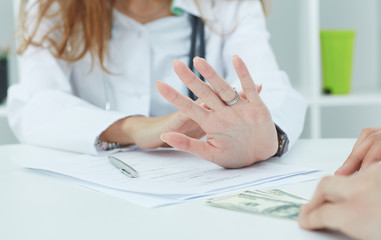 Young woman doctor refusing bribe.