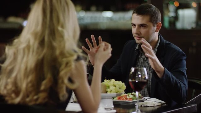 back view of curling blondie telling to partner in restaurant