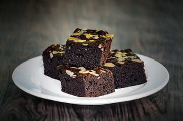 Almond Dark Brownies in white plate on wood table background.