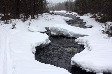 Beginning of winter. Snowing over frozen river