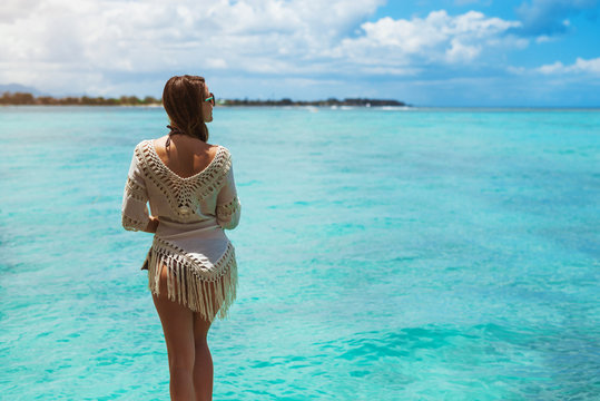 Back view of fit woman enjoying pleasant sunlight looking away.