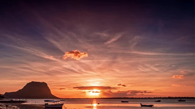 Paradise rocky tropical island at sunset time lapse. Boats on the beach and Le Morne Brabant UNESCO World Heritage Site at sunset time. Mauritius.