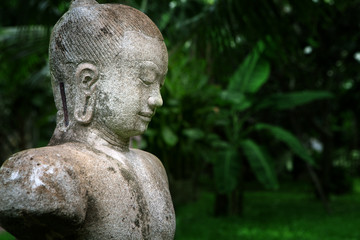 Fototapeta na wymiar close up view of old concrete Buddha statue on green back