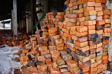 Large pile of old bricks at plant outdoor with snow.