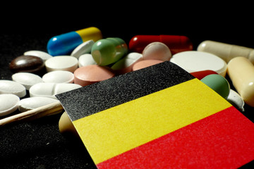 Belgian flag with lot of medical pills isolated on black background
