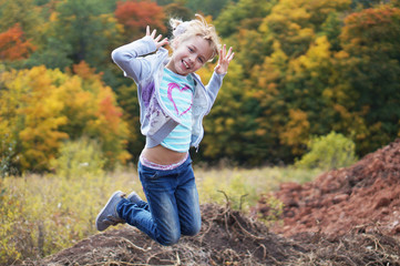The child laughs and jumps on a background autumn forest.