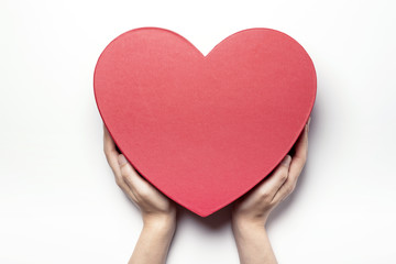 Woman hand hold a red heart gift box isolated white.