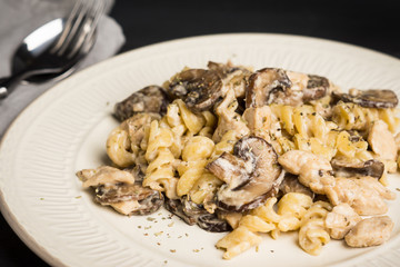 Pasta with grilled mushrooms and chicken on the dark wooden background