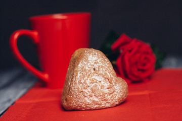 cupcake sprinkled with powdered sugar on a red napkin, mug and red flower