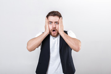 cute young frightened man with beard in shirt and waistcoat over gray background