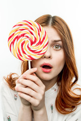 surprised woman holding a round candy in front of her eye