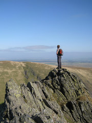 Obraz premium Man looks in to distance from a precarious ledge and contemplates