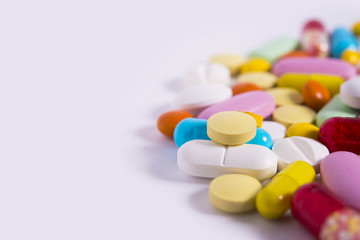 Multicolored pills and tablets on white background