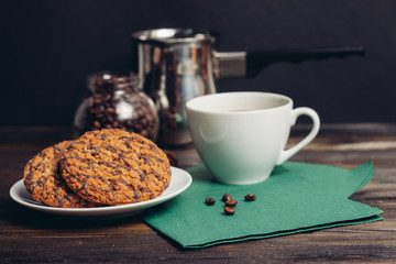 oatmeal cookies in chocolate glaze, a cup with a drink on a green napkin