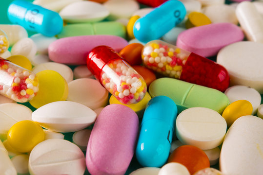 Multicolored pills and tablets on green background