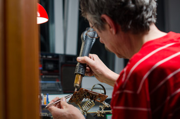 Worker repairing computer equipment with soldering iron