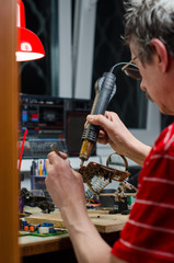 Worker repairing computer equipment with soldering iron