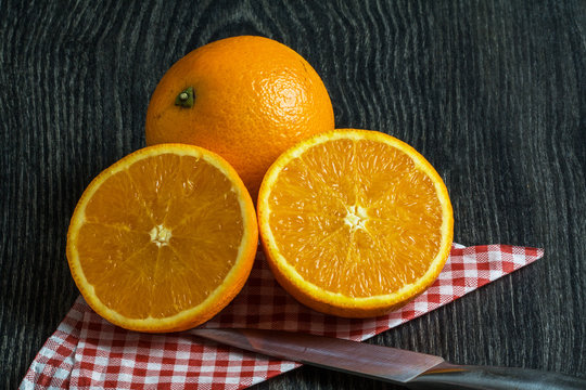 Oranges sur fond noir coupée de moitié avec couteau et serviette