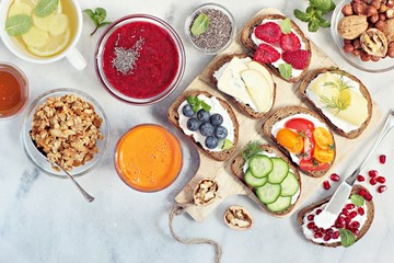 Fototapeta na wymiar Breakfast table with granola, fresh smoothie, juice and various of sandwiches. Healthy eating concept