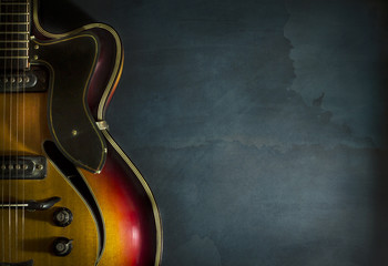 Close-up of old electric jazz guitar on a dark blue background